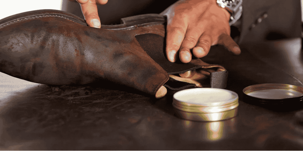 A man applying dubbin to leather shoes
