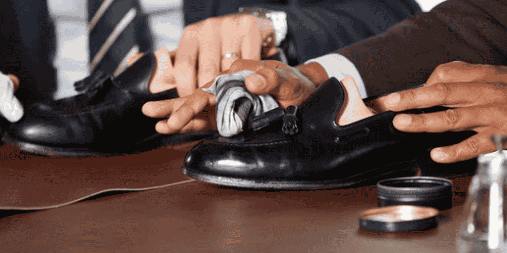 a well suited man applying dubbin on leather shoes