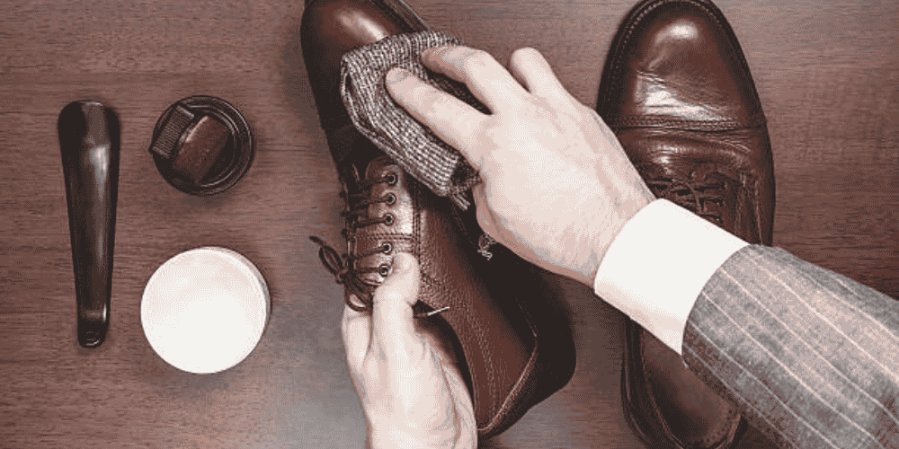 a well suited man applying wax on leather shoes